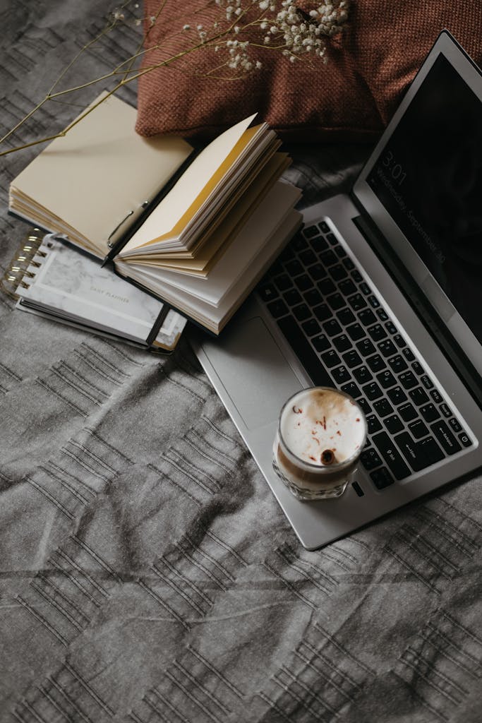 A cozy home office setup featuring a laptop, open notebooks, and a cup of coffee, promoting productivity and comfort.